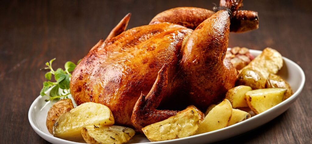 kurczak zagrodowy pieczony w całości podany na talerzu z ziemniakami