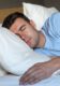 czy można spać bez poduszki - śpiący mężczyzna