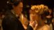 Mężczyzna delikatnie dotyka podbródka kobiety w eleganckiej sukni podczas przyjęcia przy świecach – kadr z filmu „Crimson Peak. Wzgórze krwi”.